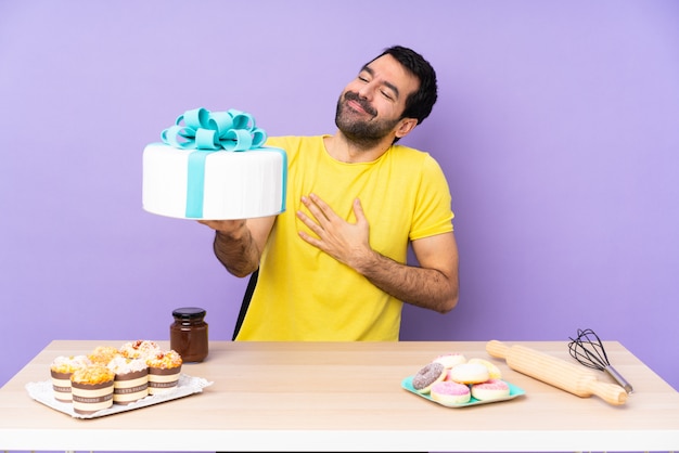 Homme dans une table avec un gros gâteau sur backgroun violet