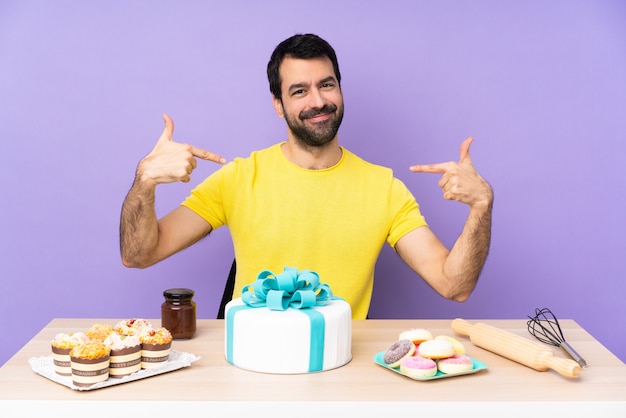 Homme dans une table avec un gros gâteau fier et satisfait de lui-même