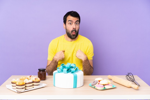 Homme dans une table avec un gros gâteau pointant vers soi