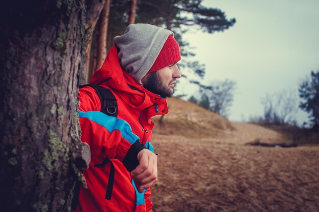 Un homme dans une veste rouge voyageant avec un sac à dos.