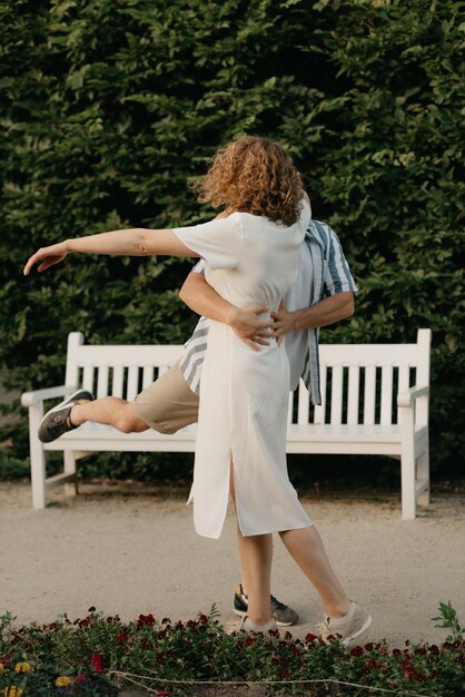 Un homme danse avec une femme aux cheveux bouclés dans le jardin le soir