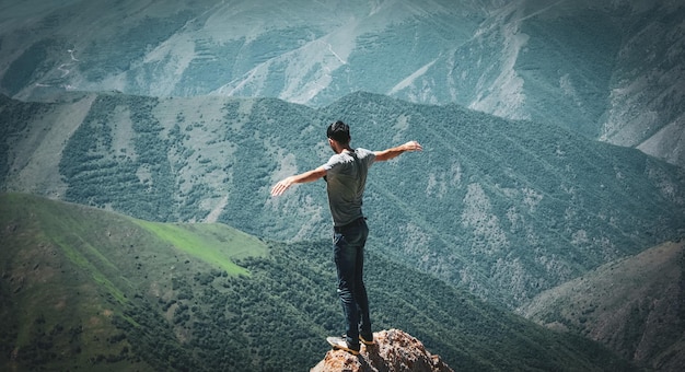 Homme debout au sommet d'une falaise au coucher du soleil