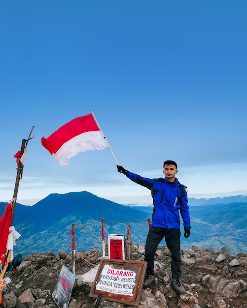 un homme debout au sommet de la montagne agitant le drapeau indonésien pour célébrer la journée de l'indonésie