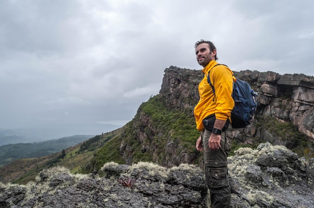 Homme debout au sommet des montagnes avec veste jaune et sac à dos en admirant la vue Trekking à Sutatausa Colombie