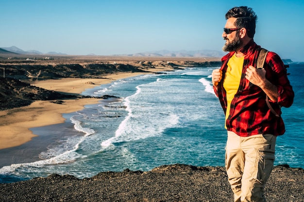 Homme debout avec barbe avec sac à dos et belle plage sauvage