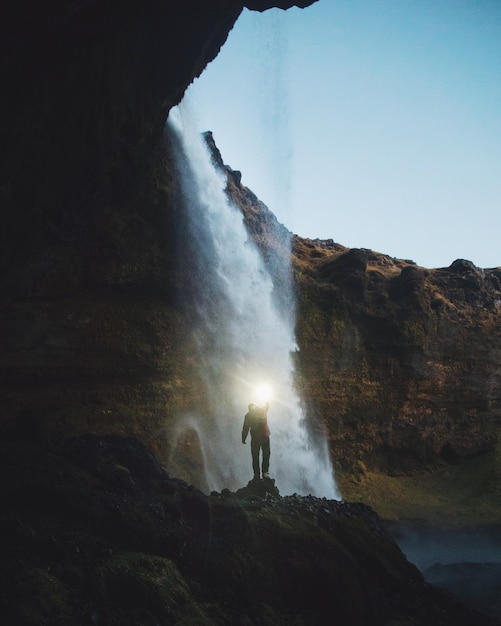 Un homme debout contre une cascade.