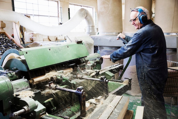 Homme Debout Dans Un Atelier De Menuiserie, Portant Des Protections Auditives, Travaillant Sur Une Machine à Bois.