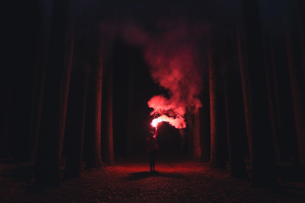 Un homme debout dans un feu éclairé la nuit.