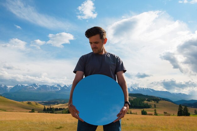 Homme debout dans les montagnes de l'altaï d'été dans la steppe de Kurai et tenant un miroir de cercle voyage créatif ...