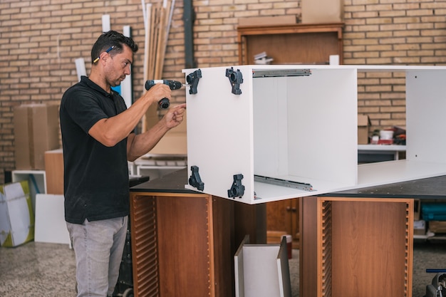 Photo homme debout devant une armoire en bois le forant dans un atelier