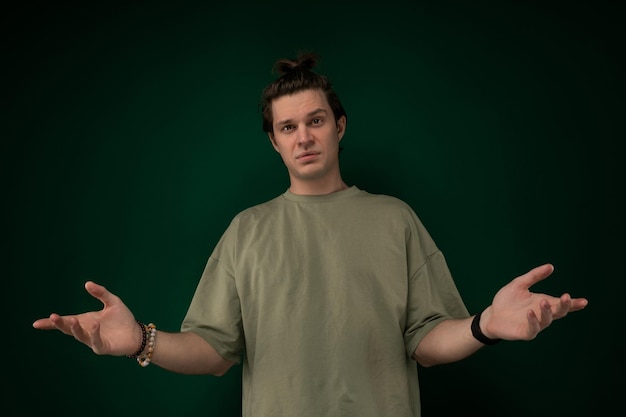 Un homme debout devant le mur vert tendant les mains.