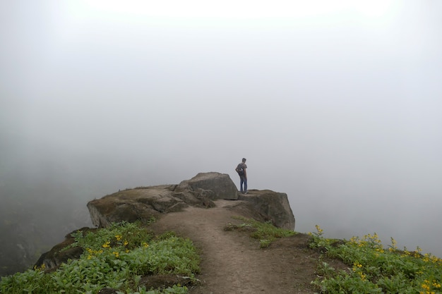 Homme Debout Sur Une Falaise Dans Une Vallée En Regardant La Route De Brume Des Fleurs