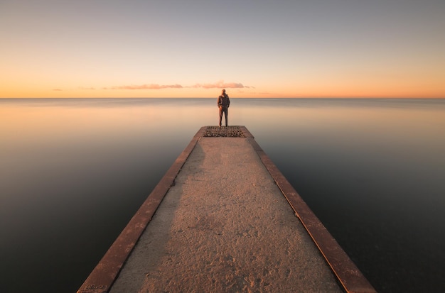 Photo un homme debout sur la jetée contre le ciel au coucher du soleil