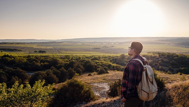 Un homme debout sur une montagne au coucher du soleil