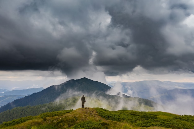 L'homme debout sur la montagne contre les nuages pluvieux