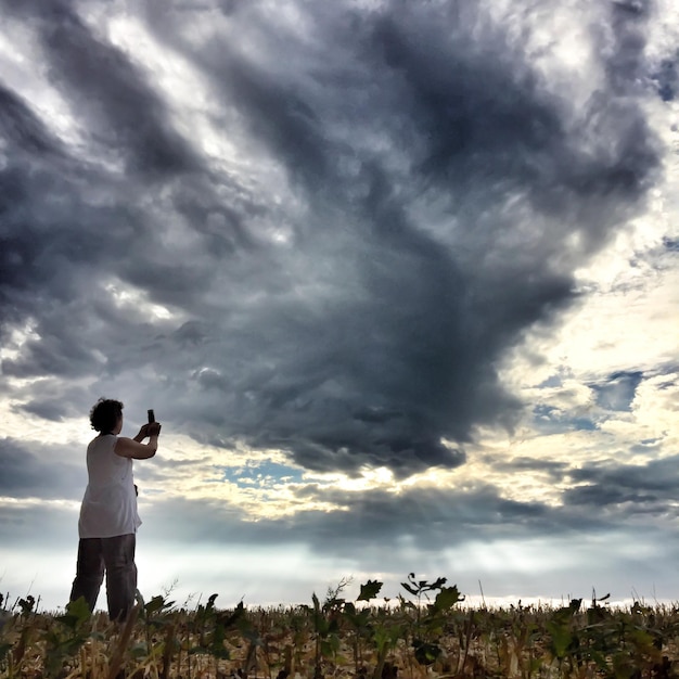 Photo un homme debout sur un paysage contre un ciel nuageux