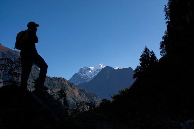 Homme debout pour regarder la vue sur les montagnes de neige, silhouette photo