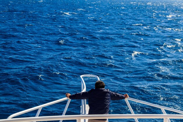 Homme debout sur la proue blanche du yacht et regardant sur la mer ou l'océan. Concept de vacances de luxe. Vue arrière