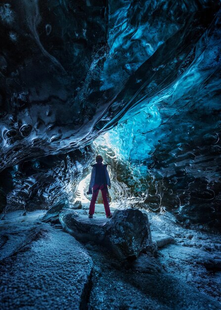 Un homme debout sur un rocher dans une grotte gelée