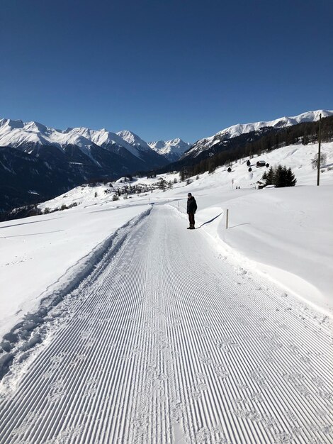 Un homme debout sur une route enneigée contre un ciel dégagé