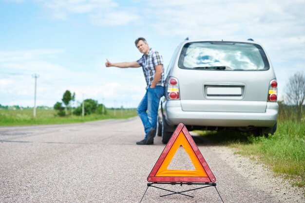 Homme debout sur la route près de la voiture en attente d'aide