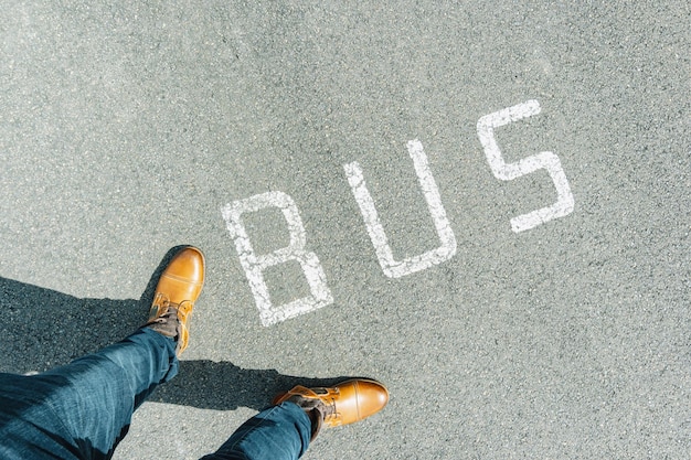 Homme debout sur la rue de la ville d'asphalte grunge avec bus de texte blanc, point de vue perspective