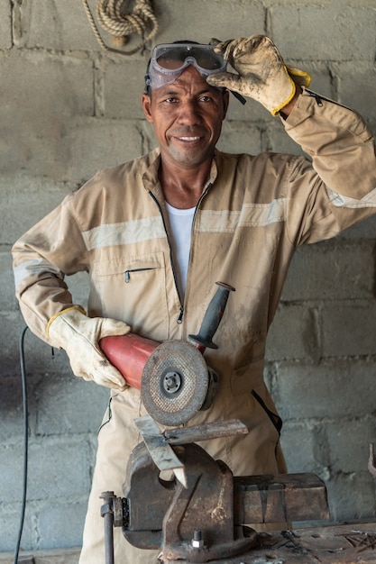 Homme debout sur son lieu de travail souriant et regardant la caméra