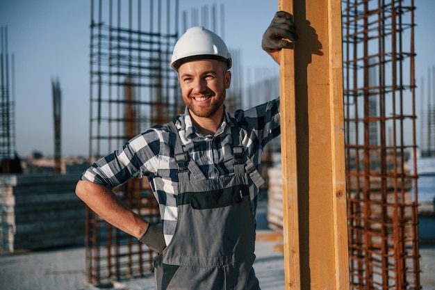 Photo l'homme debout et souriant travaille sur le chantier pendant la journée