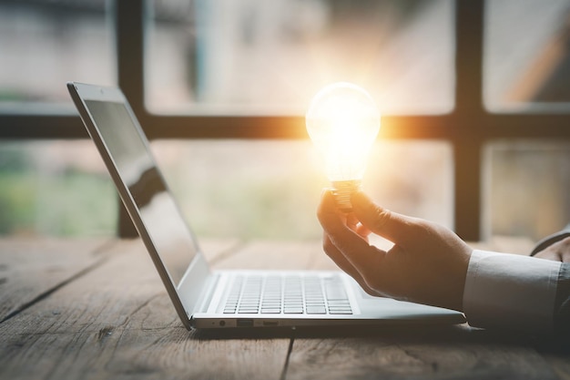 Un Homme Debout Tient Une Ampoule Incandescente Nouvelle Idée Créative Remue-méninges Sur L'innovation élaboration De Stratégies Pour Faire Croître Et Rentabiliser L'entreprise Planification De La Stratégie D'exécution Du Concept Et Gestion Des Bénéfices