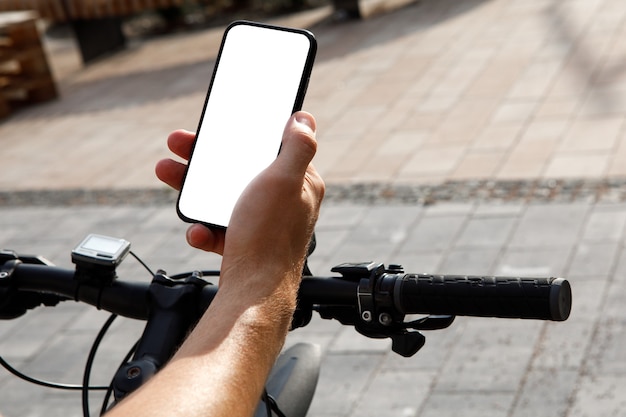 Homme debout avec vélo et montrant le téléphone avec écran blanc vierge