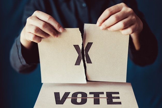 Homme déchirant le papier brun avec x marque au-dessus de la boîte de vote