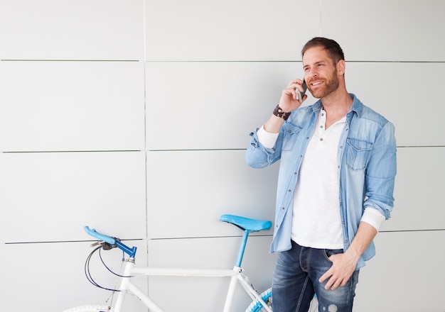 Homme décontracté à côté d&#39;un vélo vintage avec le mobile