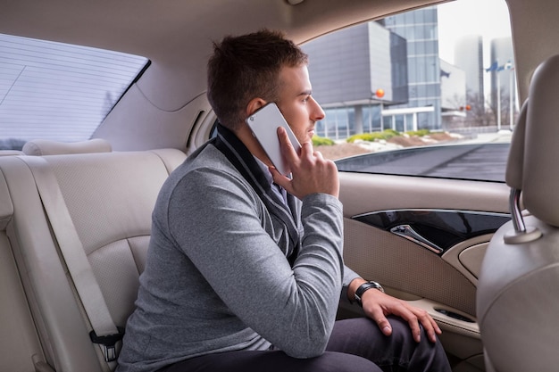 Homme Décontracté Dans Une Chemise Grise Parlant Par Smartphone Dans La Voiture.