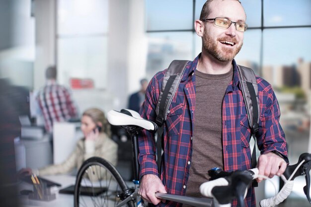 Homme décontracté portant un vélo dans un bureau moderne