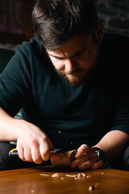 Homme découpant d'un bloc de bois avec un couteau