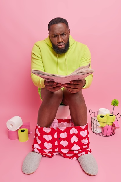 l'homme découvre des nouvelles de nouvelles poses de journaux sur la cuvette des toilettes souffre de constipation porte des boxers à capuche et des pantoufles passe son temps libre dans les toilettes