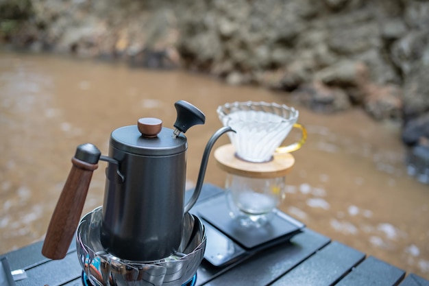 Homme dégoulinant de café chaud et camping près de la rivière au parc naturel. Activité de plein air et détente en vacances.