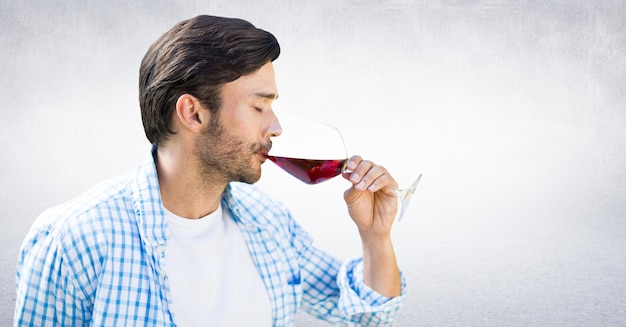 Homme dégustant du vin contre un mur blanc