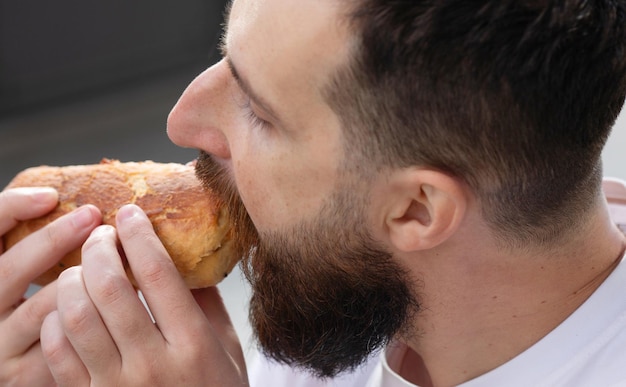 L'homme déjeune. Il regarde son sandwich et le mange immédiatement.