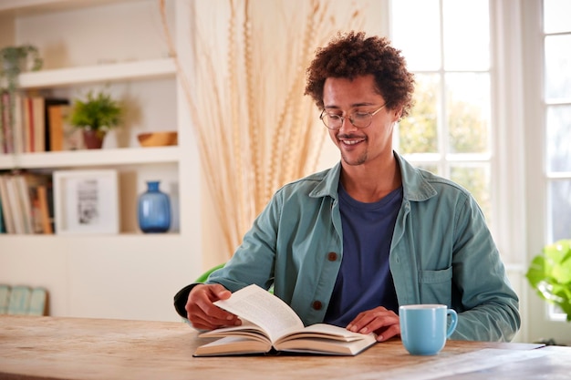 homme, délassant, chez soi, séance table, lecture, livre, à, boisson chaude