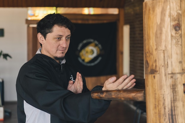 Photo un homme démontre la technique essentielle du wing chun tan sao dans un dojo d'arts martiaux