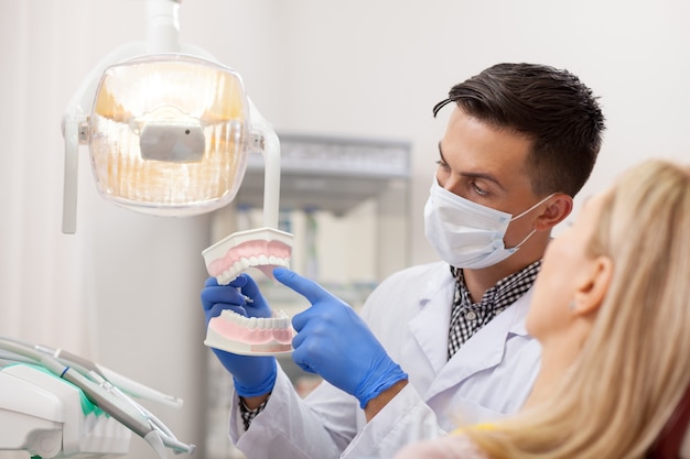 Homme dentiste expliquant à sa patiente le soin des dents