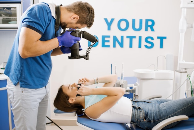 Un homme dentiste prend une photo des dents des patients