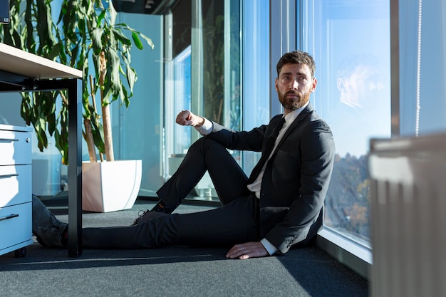 Homme déprimé assis sur le sol du bureau, employé déçu et licencié