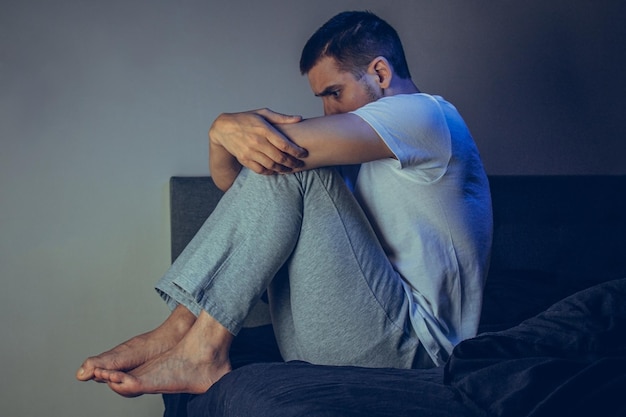 Homme déprimé assis sur le sol avec la tête baissée et appuyé contre le mur Dans des sentiments frustrés Le concept de troubles mentaux La peur de la psychose de la schizophrénie