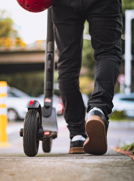 Homme de derrière marchant avec une planche à roulettes électrique dans la ville