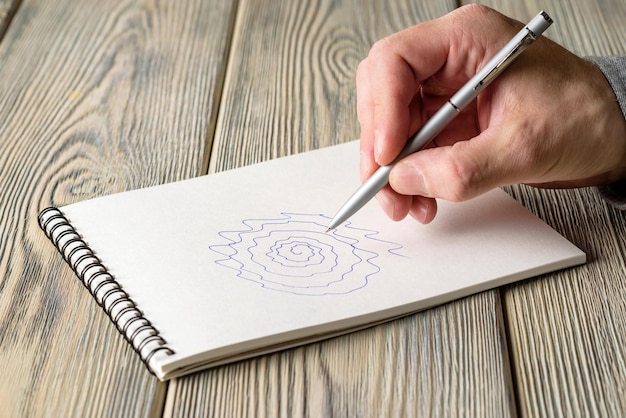 Un homme dessine une spirale inégale dans un cahier Test de tremblement essentiel et de la maladie de parkinson