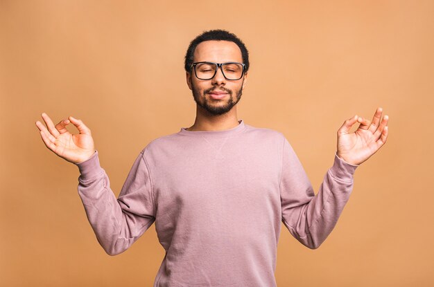 Homme détendu concentré debout avec les yeux fermés, se détendre tout en méditant, essayant de trouver l'équilibre et l'harmonie