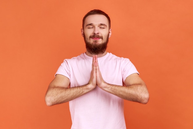 Un homme détendu debout dans une pose de yoga et essayant de se détendre garde les paumes ensemble