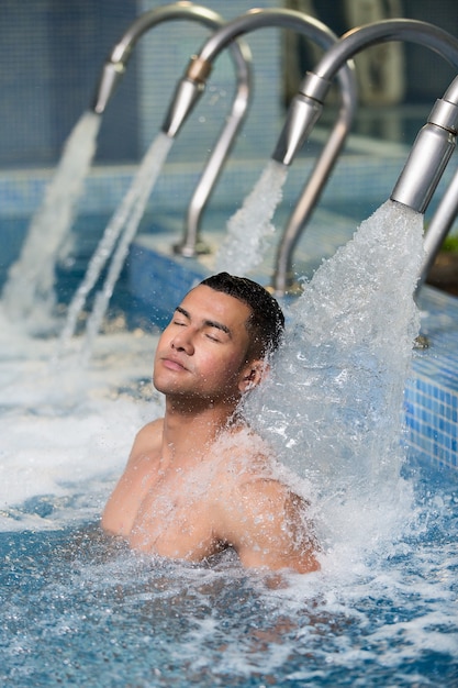 Homme détendu sous la douche dans la piscine